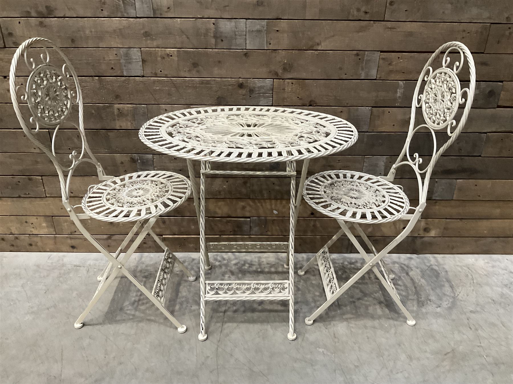 Cast metal bistro set including ornate oval garden table and two matching chairs