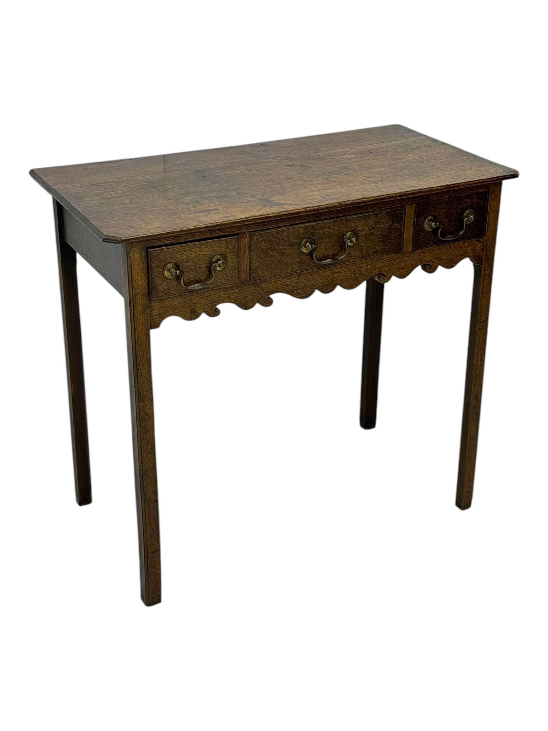 18th century oak lowboy, rectangular moulded top over three frieze drawers with brass swing handles, scalloped apron, on slender square section supports