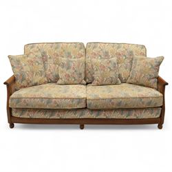 Ercol – bergère four piece suite, including armchair, two seat sofa, three seat sofa and footstool, all with removable floral upholstered cushions, the frames with side caning and rounded arm supports in stained beech

Three seat (H 87cm, D 89cm, W 196cm)
Two seat (H 87cm, D 89cm, W 137cm)
Armchair (H 87cm, D 89cm, W 87cm)
Footstool (H 28cm, D 55cm, W 55cm)