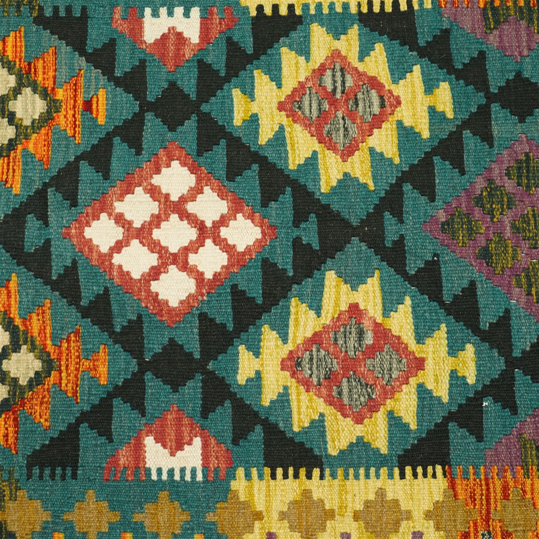 Maiman kilim, woven with an arrangement of multicoloured diamonds on a dark ground with contrasting ivory and ochre highlights, enclosed by a broad border featuring alternating geometric devices in green, mustard, red and blue