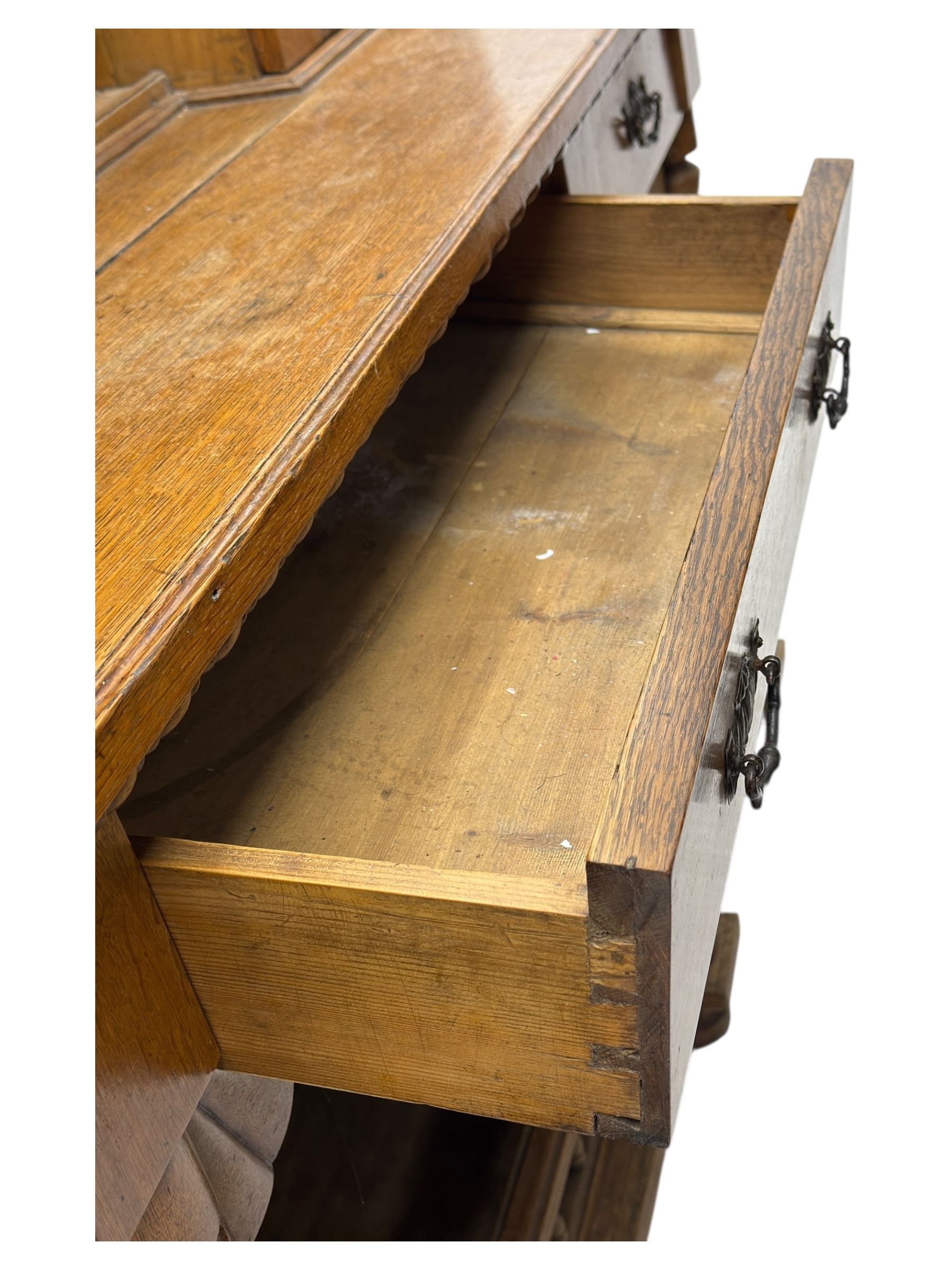 Late 19th century pine dresser, the projecting cornice with dentil and spindle moulded frieze above a three-tier plate shelves, flanked by glazed doors, the base fitted with three frieze drawers over arched apron and carved floral panelled cupboard doors, raised on turned feet