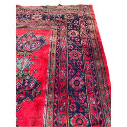Antique Turkish crimson ground carpet, the field decorated with five alternating rows of pole medallions with lozenges and stylised plant motifs, the multi-band indigo border with repeating flower heads and branches