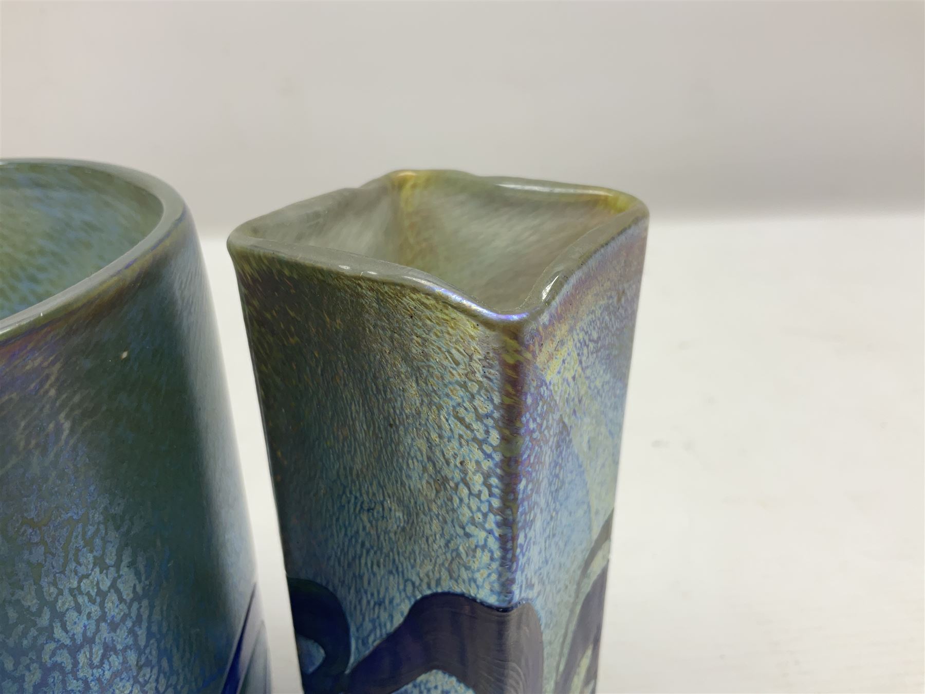 Two Isle of White glass vases, by Alum Bay Glass, both with blue swirl design upon an iridescent mottled blue/green ground, together with a Gozo Glass vase of pebble form, with similar design, H12cm