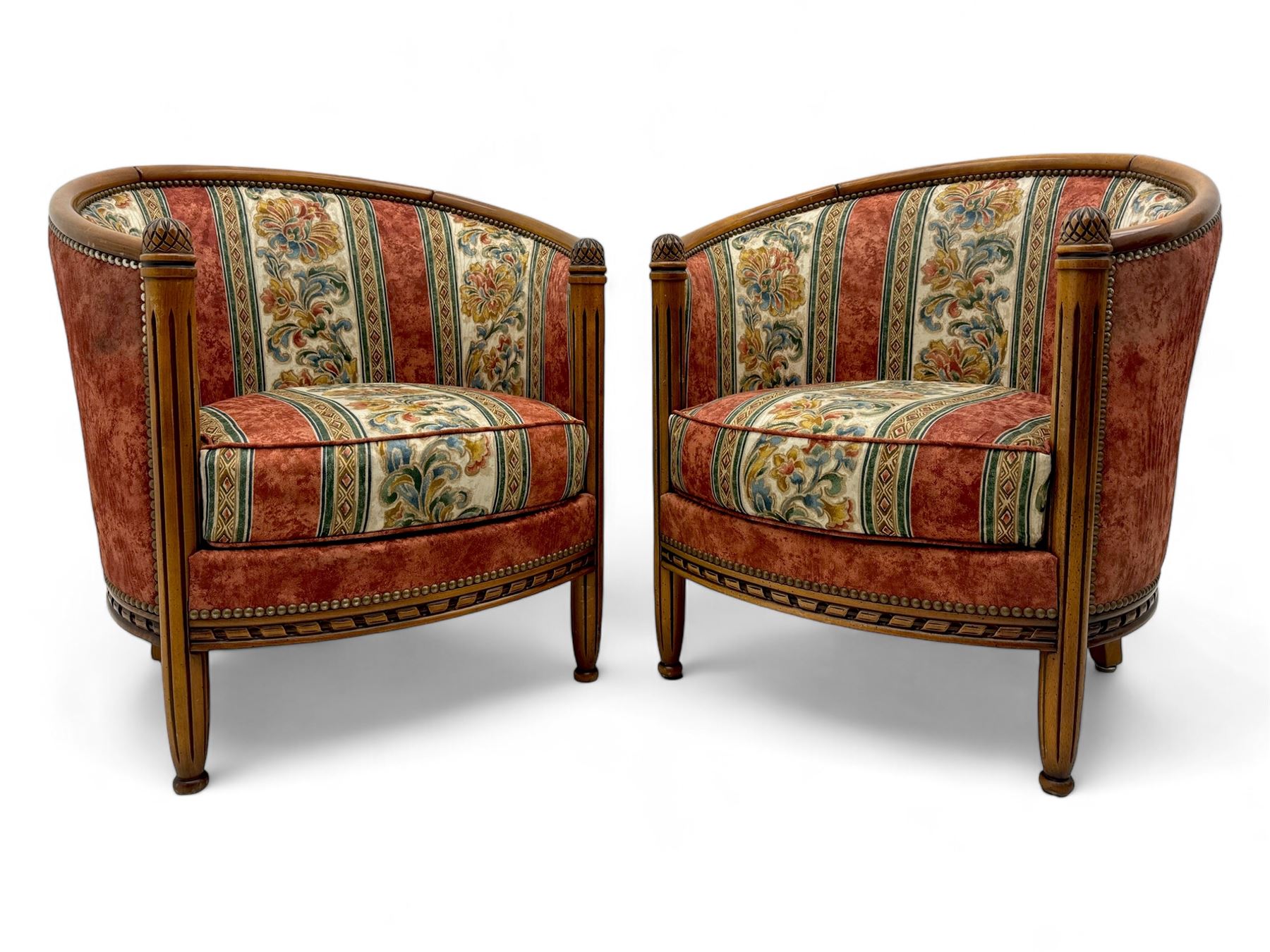 Pair of cherry wood framed tub-shaped armchairs, upholstered in striped floral fabric with brass stud trim, carved walnut frame with fluted supports capped with pinecone finials, on turned feet