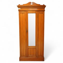 Early 20th century satin walnut wardrobe and dressing table, including a tall single wardrobe with mirrored door beneath a shaped cornice and moulded pediment, (H 205cm, D 39cm, W 91cm) and a matching dressing chest with glazed lift-top compartment and three drawers, mirror supported by scrolled uprights with flanking open shelves (H 170cm, D 45cm, W 84cm)