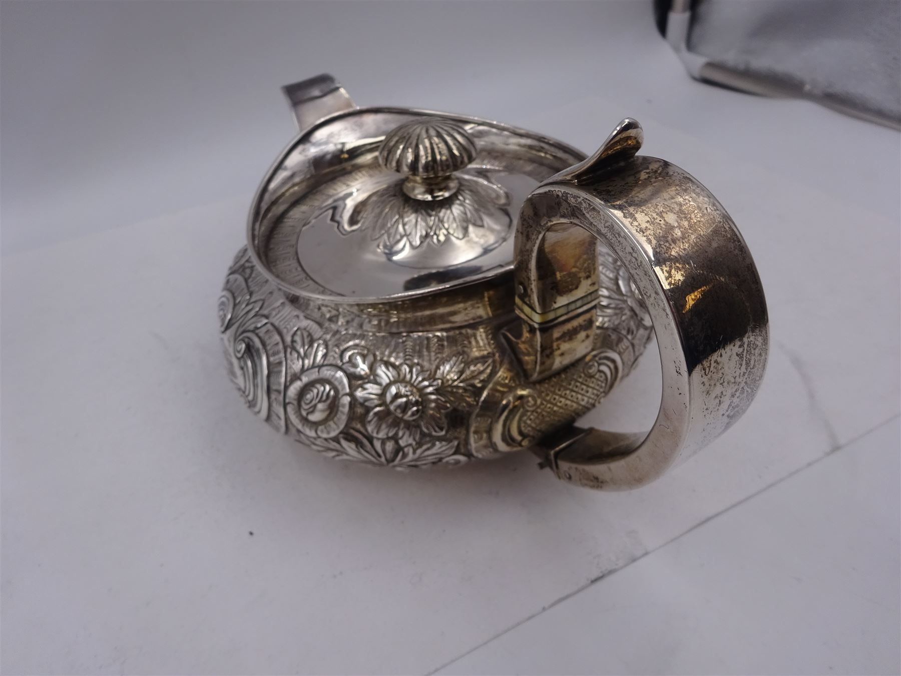 George III Irish silver teapot, of squat circular form, the body with repousse and chased floral and C scroll decoration, with capped C handle and ivory insulators, engraved to base 'Presented to Troop Sergeant Major John Percival, of the 4th Dragoon Guards by Alex D. Tait, Esq, late Captain in that corps as a mark of approbation of his steady and upright conduct when Sergeant Major of his Troop, Dublin, June 2nd 1843', hallmarked William Law, Dublin 1817, H12.5cm, This item has been registered for sale under Section 10 of the APHA Ivory Act