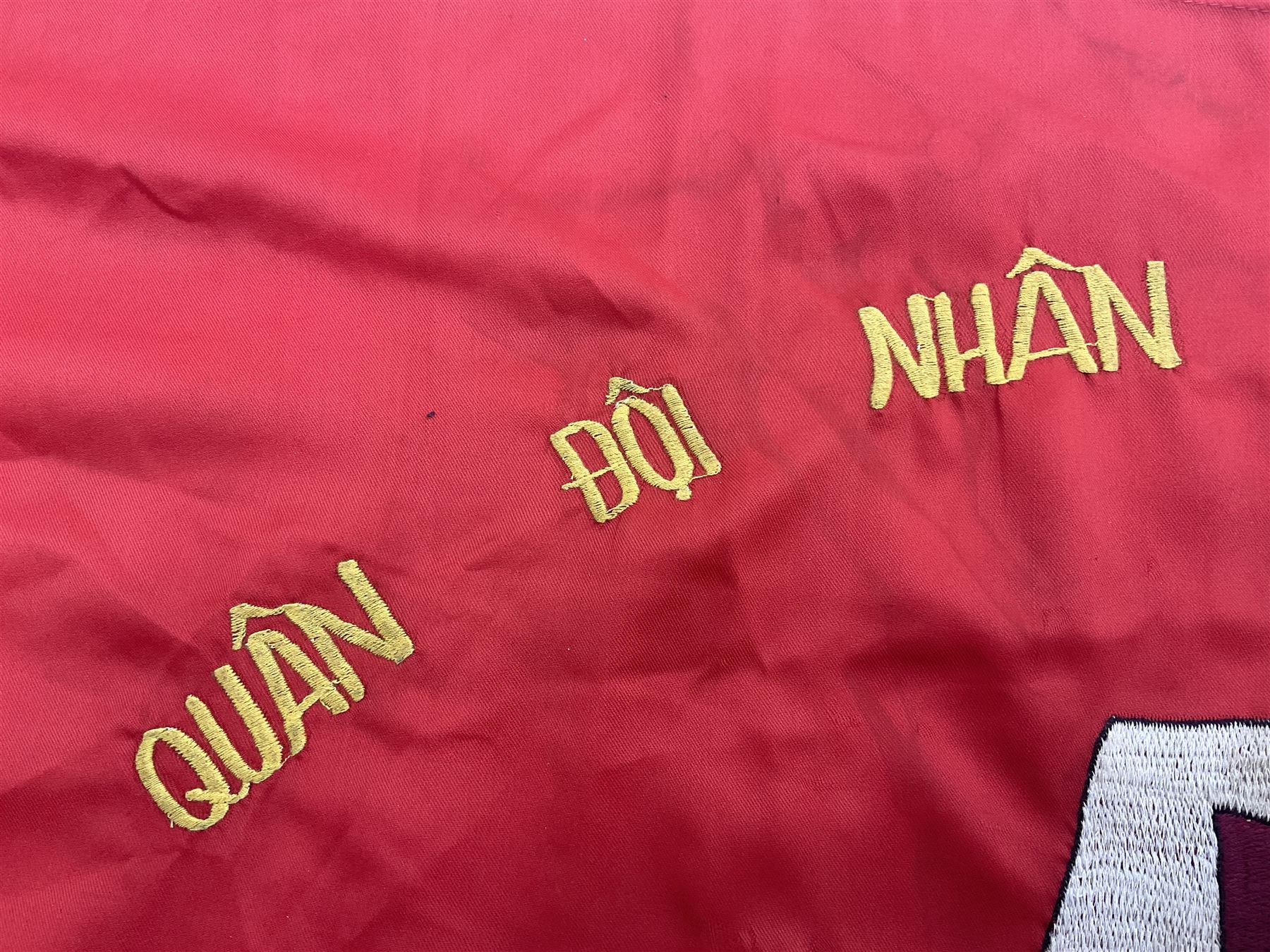 1960s North Vietnam banner embroidered in yellow thread on a red ground, roughly translates as 'Peoples Army of Viet Nam. Warriors of Viet Nam Determined To Keep The Country 1964' around a central military crest with the motto 'Warriors Keep The Country'; tassels to three sides 70 x 100cm