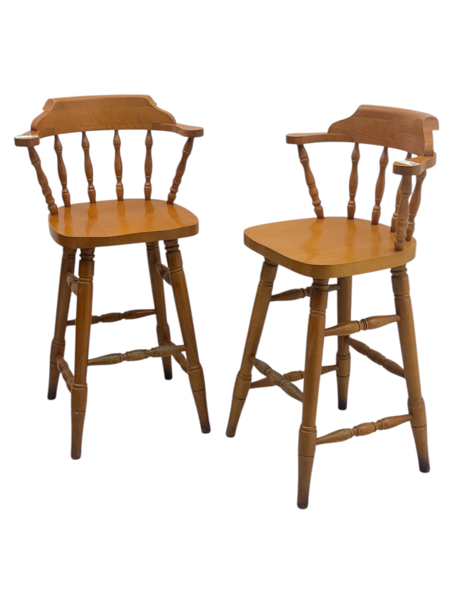 Pair of late 20th century beech bar stools, with curved top rail and turned spindle back, shaped seat over four turned legs united by multiple stretchers