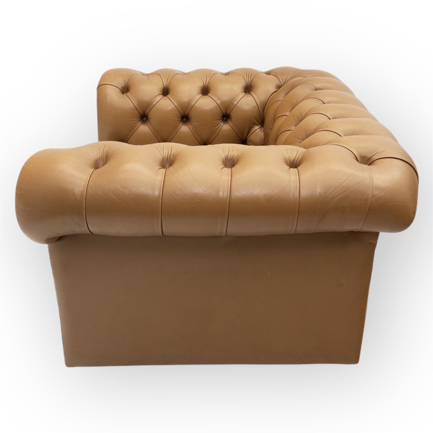 Contemporary set of two tan leather armchairs, comprising a deep-buttoned chesterfield and a matching wingback chair, both with rolled arms, studded borders