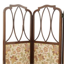 Edwardian inlaid mahogany three-fold screen, each panel with shaped cresting and satinwood line inlaid frame, with intersecting astragal bars, lower panels upholstered in floral fabric, hinged folding action on brass hinges