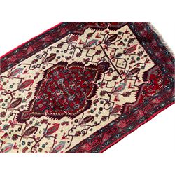 North West Persian Saveh crimson ground runner rug, the three lozenge pole medallions in an ivory field, surrounded by stylised plant motifs, the guarded border decorated with repeating geometric patterns