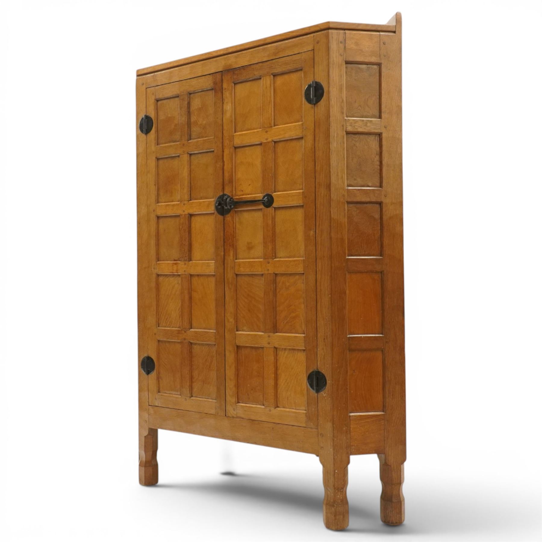 Mouseman - 1940's adzed and panelled oak corner cupboard, the raised quarter-gallery back over twin adzed panelled doors with wrought iron fittings and latch, enclosing three shaped shelves, raised on turned octagonal supports, with carved mouse signature in relief, by the workshop of Robert Thompson of Kilburn Provenance: purchased directly from the Kilburn workshop in the late 1940s