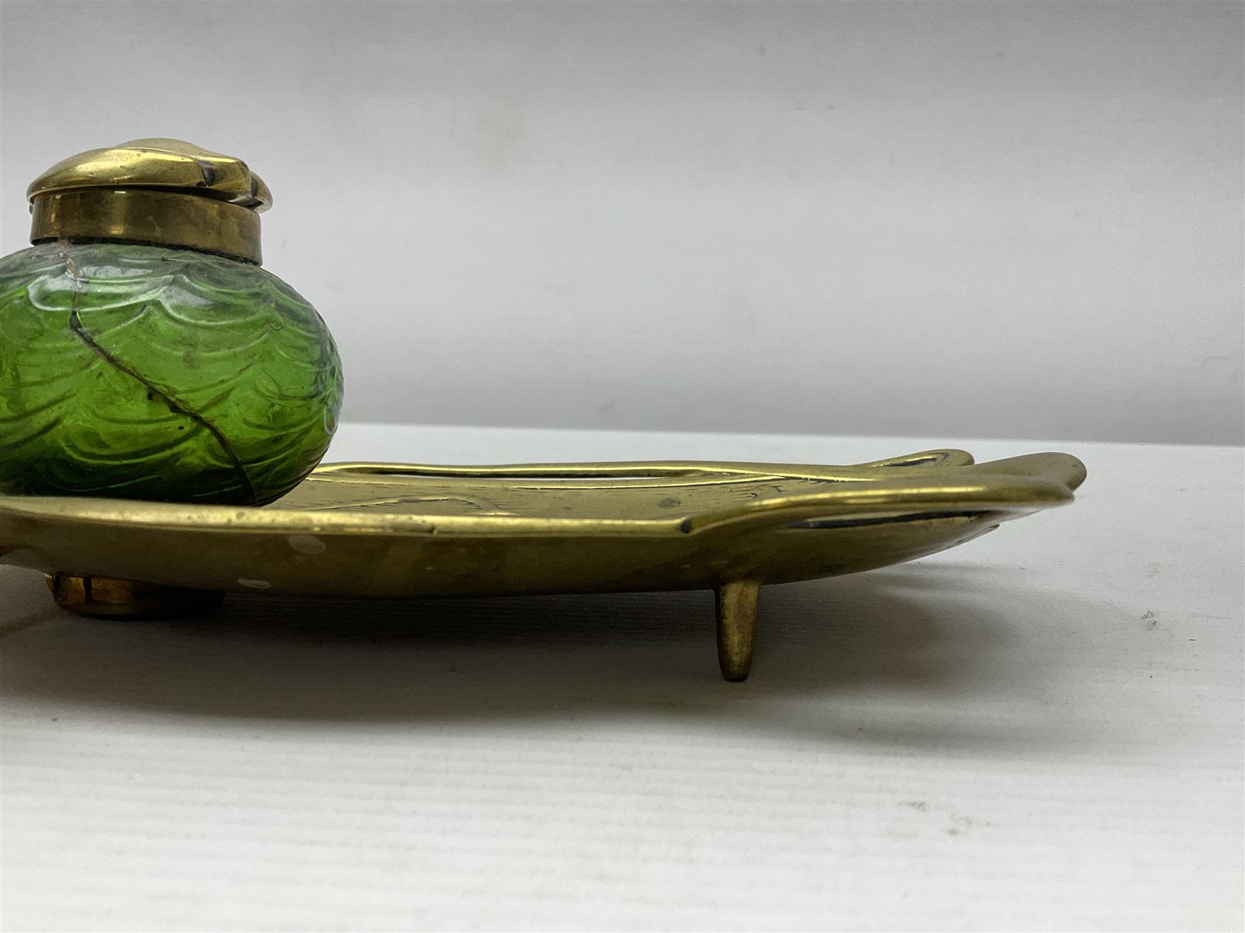 Art Nouveau Geschutzt brass desk stand, with stylised whiplash relief decoration, with removable Loetz style green glass inkwell, stamped to the base, H8cm
