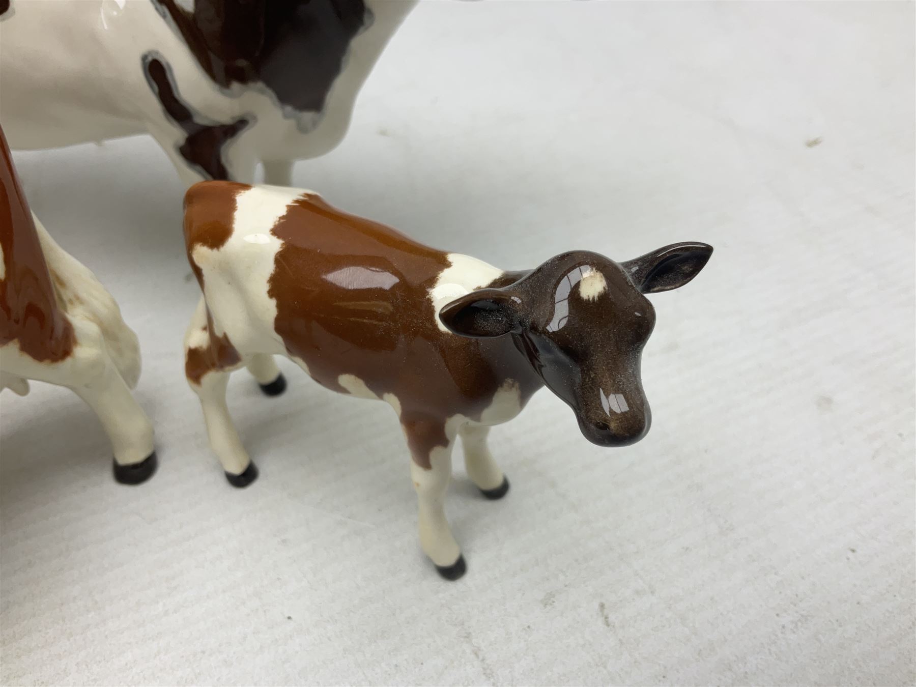 Five Beswick figures of cattle Comprising Ayrshire Bull Ch Whitehill Mandate, no 1454B, three Ayrshire Cow Ch Ickham Bessie, no 1350 and Ayrshire Calf, no 1249B, all with printed marks beneath