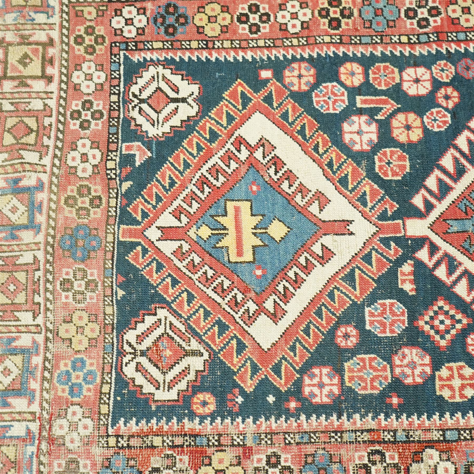 Vintage Caucasian Shirvan hand-knotted rug, indigo field with an arrangement of geometric diamond medallions and stylized tribal motifs within multiple patterned borders, with fringe ends 