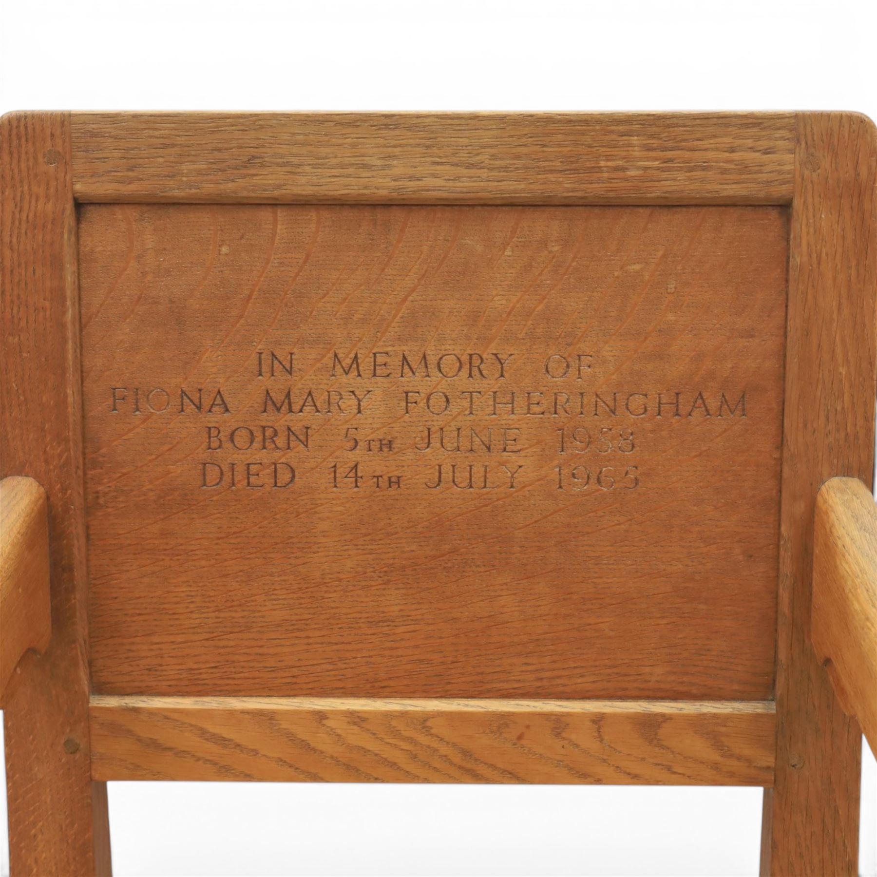 Mouseman - oak panel back carver armchair, with commemorative back panel engraved 'In memory of Fiona Mary Fotheringham Born 5th June 1958 Died 14th July 1965', above tan seat with brass studded trim, with carved Mouse signature, by Robert Thompson's of Kilburn