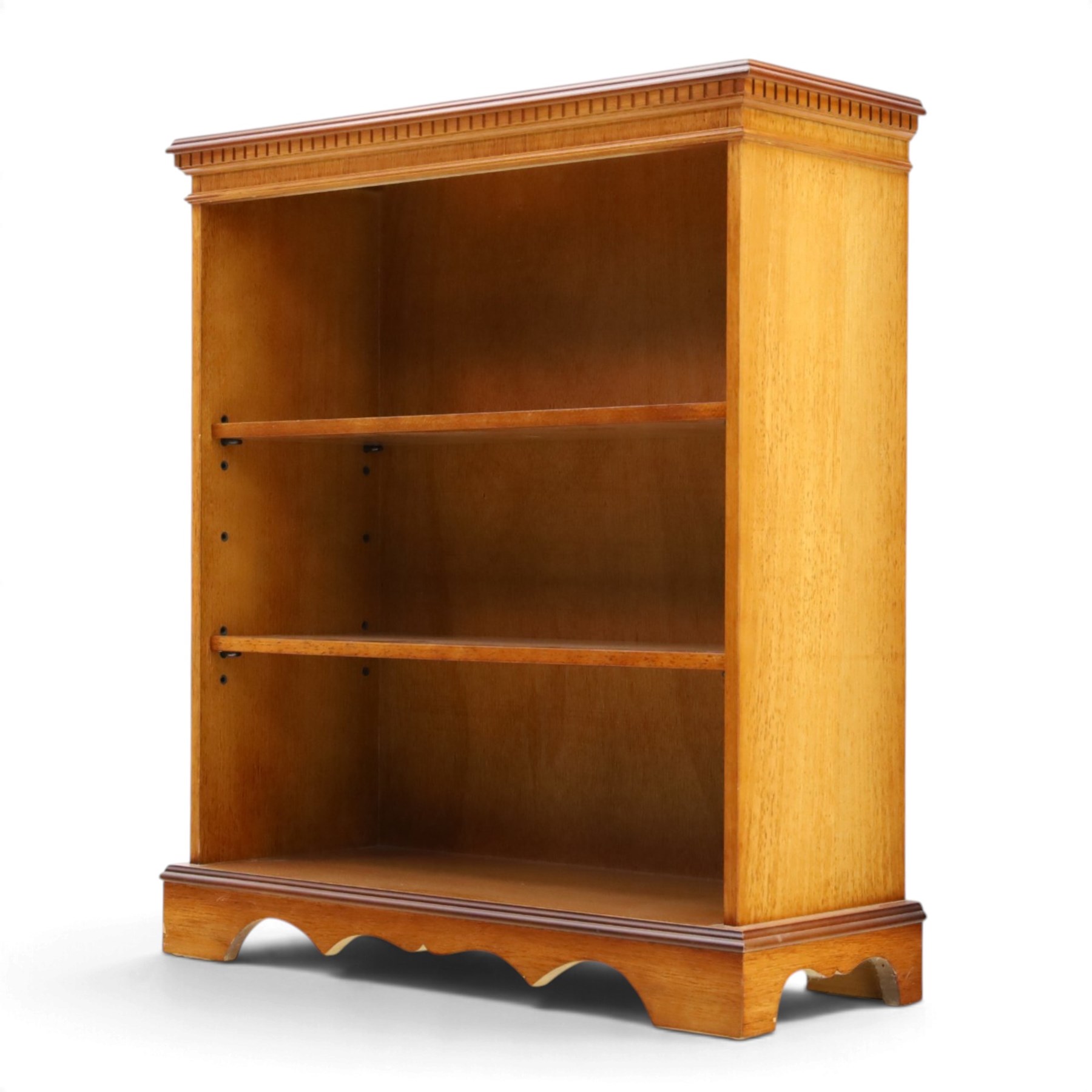Contemporary mahogany and yew wood open bookcase, dentil cornice above two adjustable shelves, shaped apron and bracket feet 