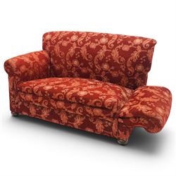 Edwardian hardwood framed petite two seat settee with single drop-arm, traditional shape with rolled arms, the drop-end with lever action adjustable height, the sprung back and seat upholstered in crimson foliate patterned fabric, on compressed bun feet