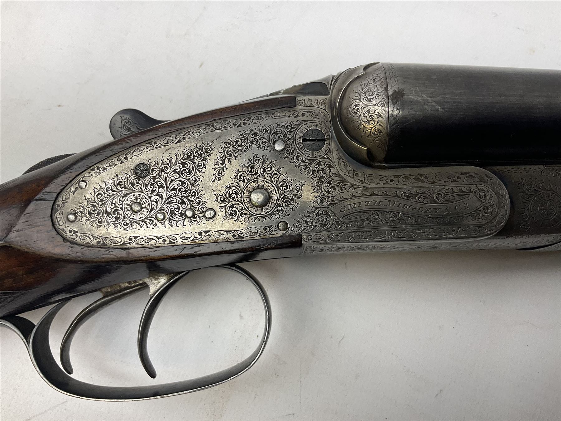 Smith Midgley Bradford 12-bore side-by-side double barrel side-lock ejector shotgun with 71cm barrels, engraved action with patented top lever, ivy leaf fences and top safety, walnut stock with chequered grip and fore-end, serial no.62409 to barrels and 1481 to action, L115cm overall SHOTGUN CERTIFICATE REQUIRED