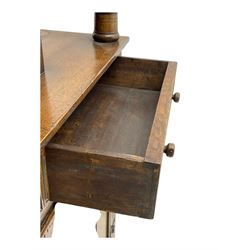 Jacobean design oak court cupboard, upper section with carved arched panelled cupboard door flanked by turned columns, beneath carved and moulded frieze, lower section fitted with two drawers over two cupboard doors with gothic arched panel decoration, raised on stile supports