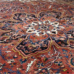 North West Persian Ahar hand-knotted carpet, madder red ground, with a large central shaped floral medallion with pendants, surrounded by angular scrolling foliate motifs incorporating rosettes, palmettes and stylised flowerheads, enclosed by ivory spandrels and a dark navy border with repeating floral motifs and meandering vines, flanked by narrow floral guard stripes, with cotton fringes
