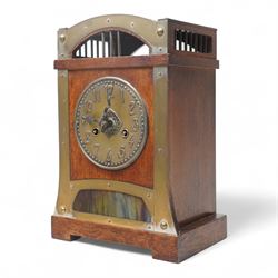 Early 20th century-German Arts & Crafts oak cased mantel clock with a two train movement by the Hamburg and American Clock Company, case with a rounded pediment and gallery to the front and sides, formerly silvered dial and brass strapwork to the front with a multi-coloured glass panel beneath, conforming hammered dial with Arabic numerals and contrasting steel serpentine hands, twin train countwheel striking movement, striking the hours and half hours on a coiled gong.
With pendulum and key.