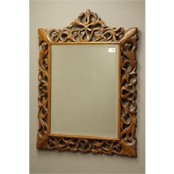  Late 20th century oak framed wall mirror carved with scrolling foliage, bevelled glass plate, 67cm x 88cm  