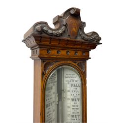 J Hicks - Hatton Garden London, - late 19th century carved oak cased Fitzroy barometer in a richly carved case with a carved crested pediment and square cistern cover, inverted opaline register reflecting FitzRoy's predictions and a scale from 27 to 31 inches of barometric pressure, with a thick bore cistern tube and adjustable rack and pinion twin vernier, fitted with a glazed snail bulb mercury thermometer recording the air temperature in both Fahrenheit and Celsius. Mercury clean and present.
James Joseph Hicks was born in Ireland, however, early in his life he moved to London where he was apprenticed to the instrument maker Louis P Casella. In 1860 he went into business in his own right as a scientific instrument maker at 8 Hatton Gardens. In 1864 he was granted membership to the British Meteorological Society and exhibited instruments at the Royal Society Exhibitions between 1876 and 1913. Hicks was one of London's most prolific and eminent barometer makers. 