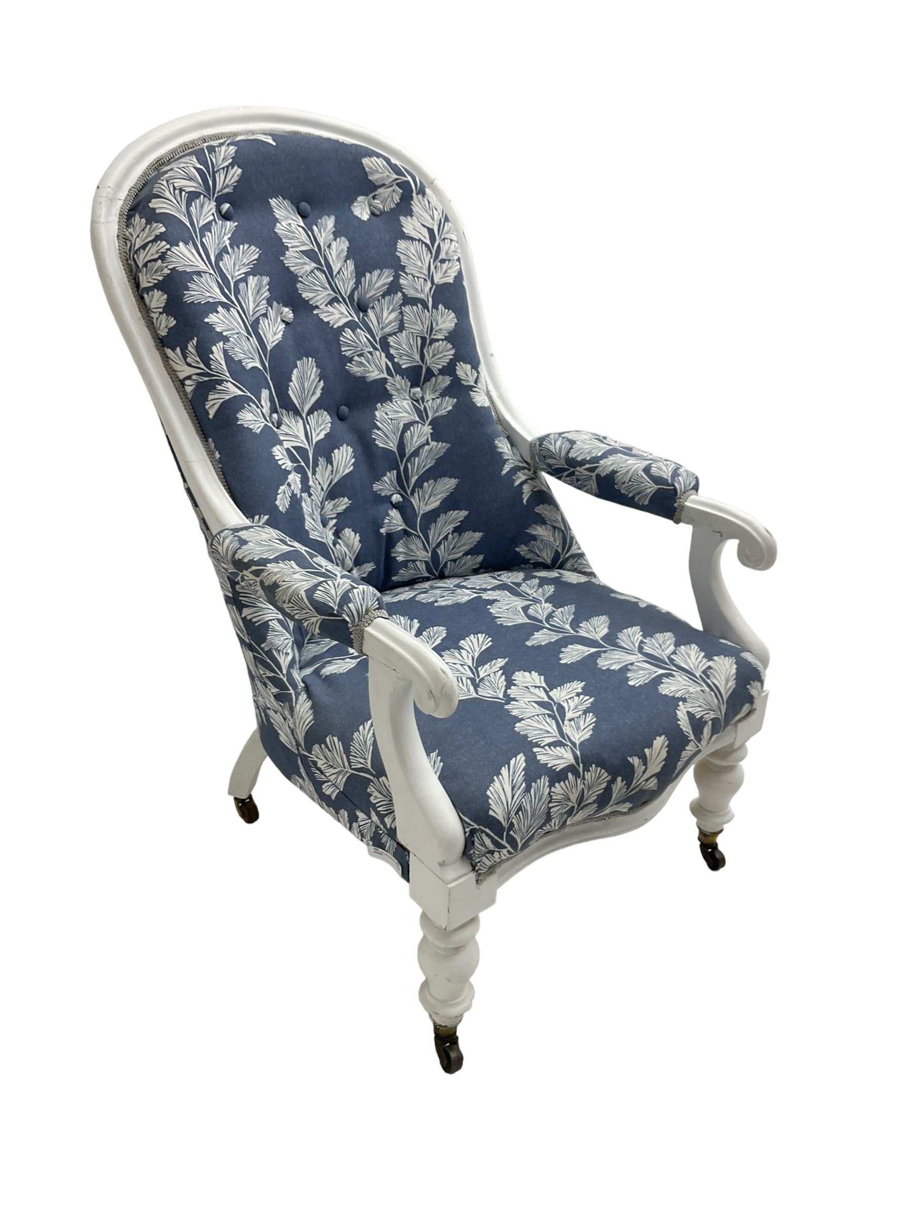 Victorian white painted open armchair, upholstered in blue fabric decorated with trailing leaf pattern, scrolled arm terminals on turned front supports with castors
