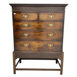 George III mahogany chest on stand, projecting decorative moulded cornice over blind fret carved frieze, fitted with two short over three long graduating cock-beaded drawers, the stand with chamfered supports united by stretcher