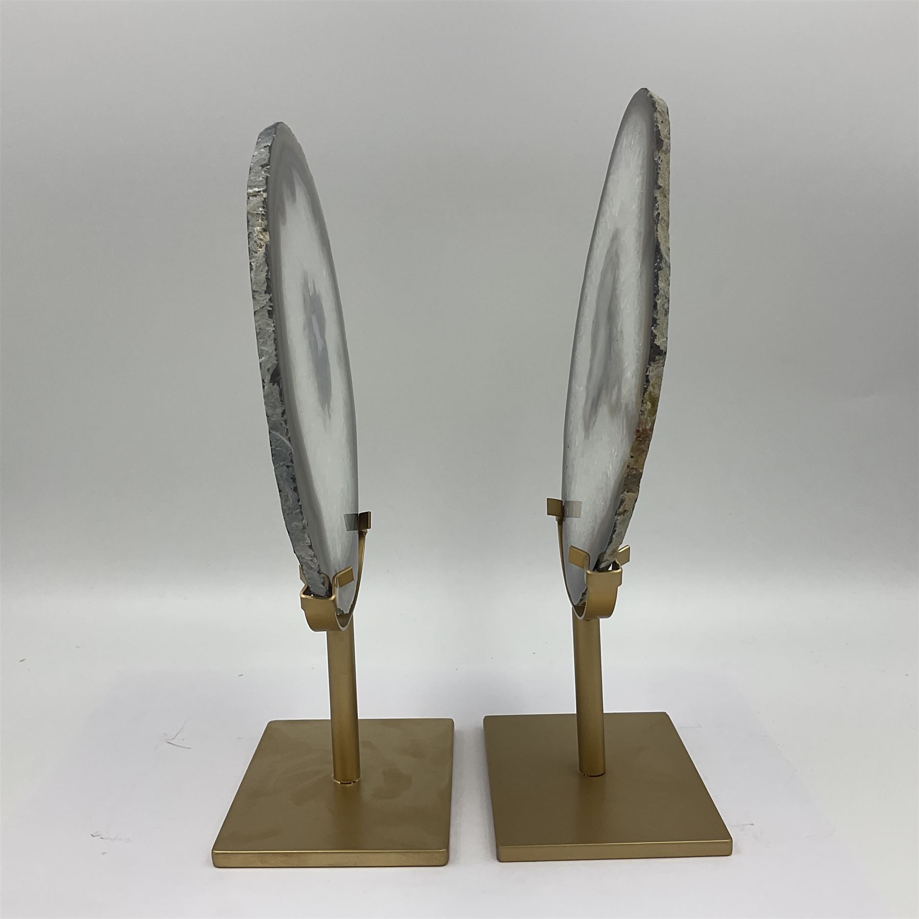 Pair of white agate slices, polished with rough edges raised upon gilt metal stands, H24cm