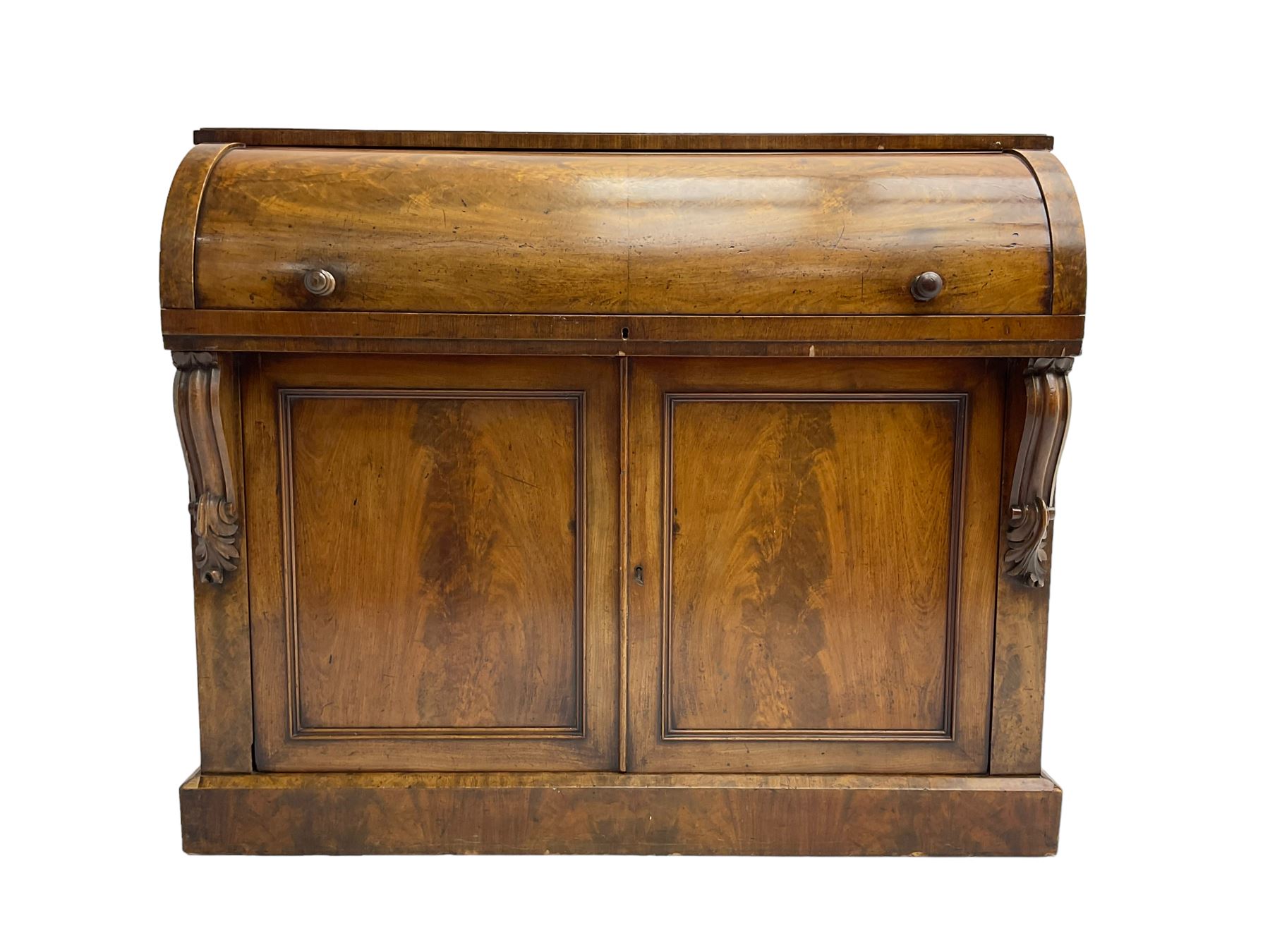 Victorian mahogany roll-top writing desk, top concealing fitted interior with pigeonholes and three drawers, the trisector inset writing surface with writing slope, base fitted with panelled cupboard enclosing single shelf, decorated with scrolled corbels