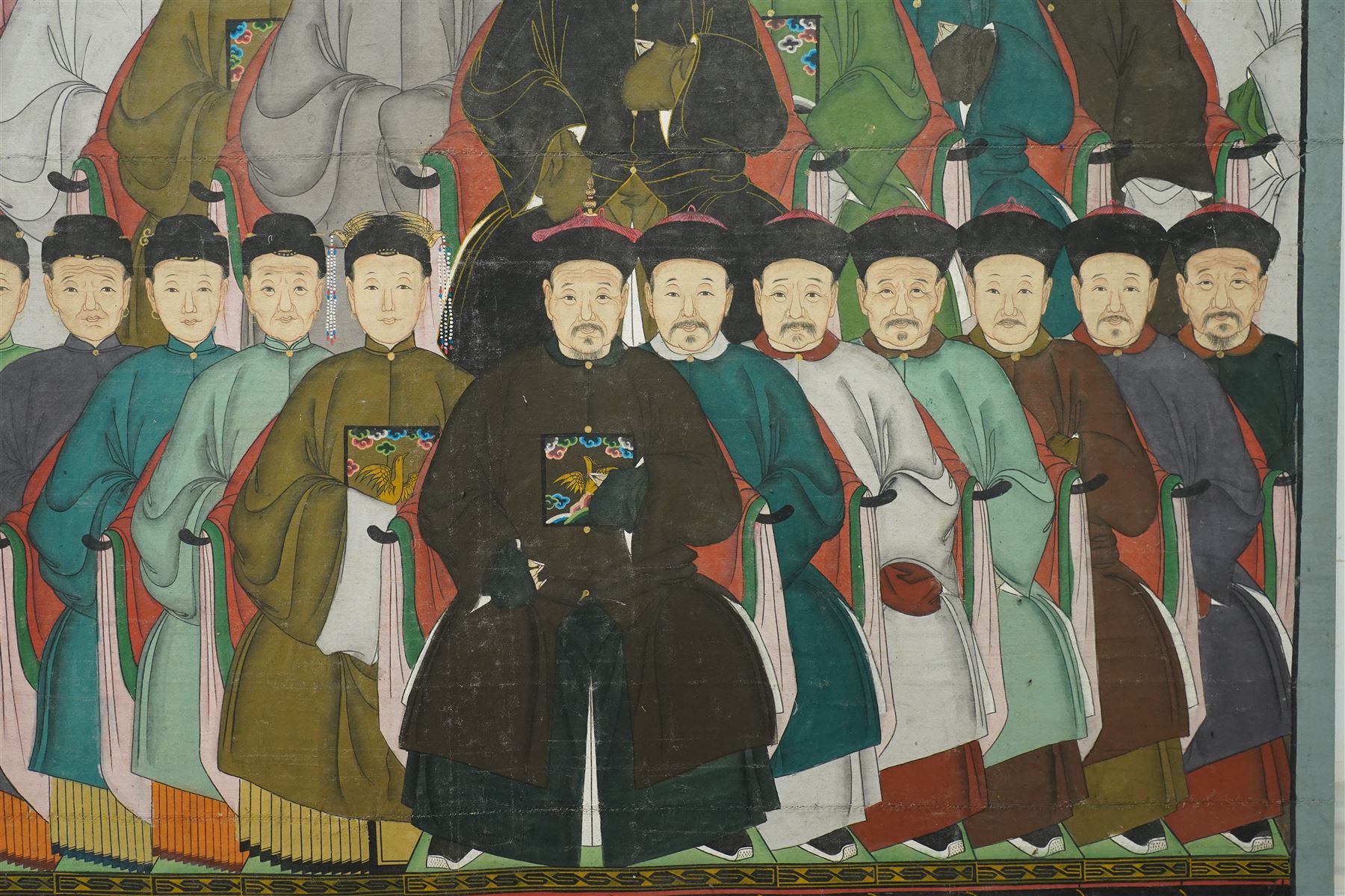 Large and impressive Chinese ancestral portrait, late Qing dynasty, gouache on stitched canvas with gilded highlights, showing thirty-eight sitters across four registers, the principal ancestors depicted before an altar table holding various ritual items, each in official dress and many wearing Golden Pheasant (Second-rank) and Silver Pheasant (Fifth-rank) Mandarin squares or 'buzi', overall 190cm x 131cm 