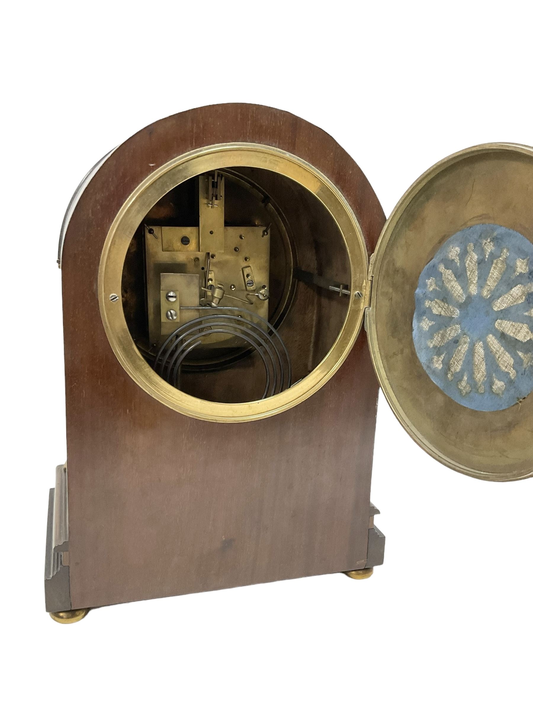 Manoah Rhodes & Son of Bradford, - Edwardian mahogany domed top mantle clock with a French 8-day movement striking the hours and half hours on coiled gong, case with inlaid stringing and raised on brass button feet, convex enamel dial with Roman numerals and steel spade hands. With pendulum and key.