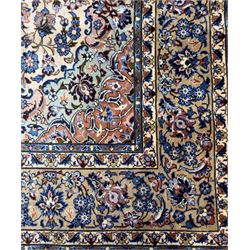 Central Persian Najafabad hand-knotted carpet, the ivory field with a central floral medallion radiating palmettes and arabesques in tones of blue, lilac and tan, enclosed by a wide navy border of scrolling vine and rosette motifs, with red spandrels and multiple guard stripes