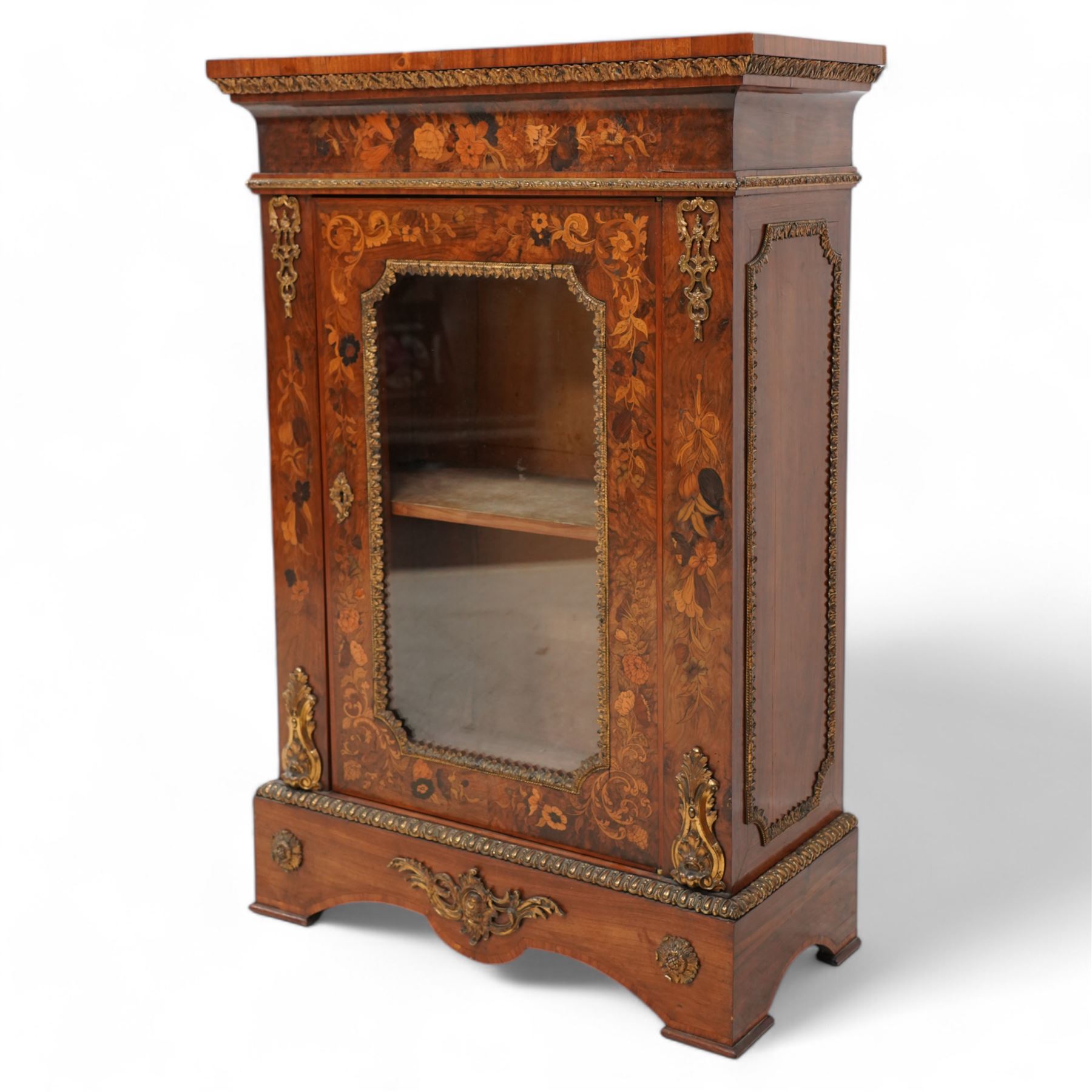 Victorian walnut and gilt metal mounted pier cabinet, rectangular top over acanthus leaf moulded gilt metal edging and floral inlaid frieze, single glazed door inlaid with scrolling leafage and flower heads, fitted with single internal shelf, egg and dart moulded lower edge over shaped skirt base 