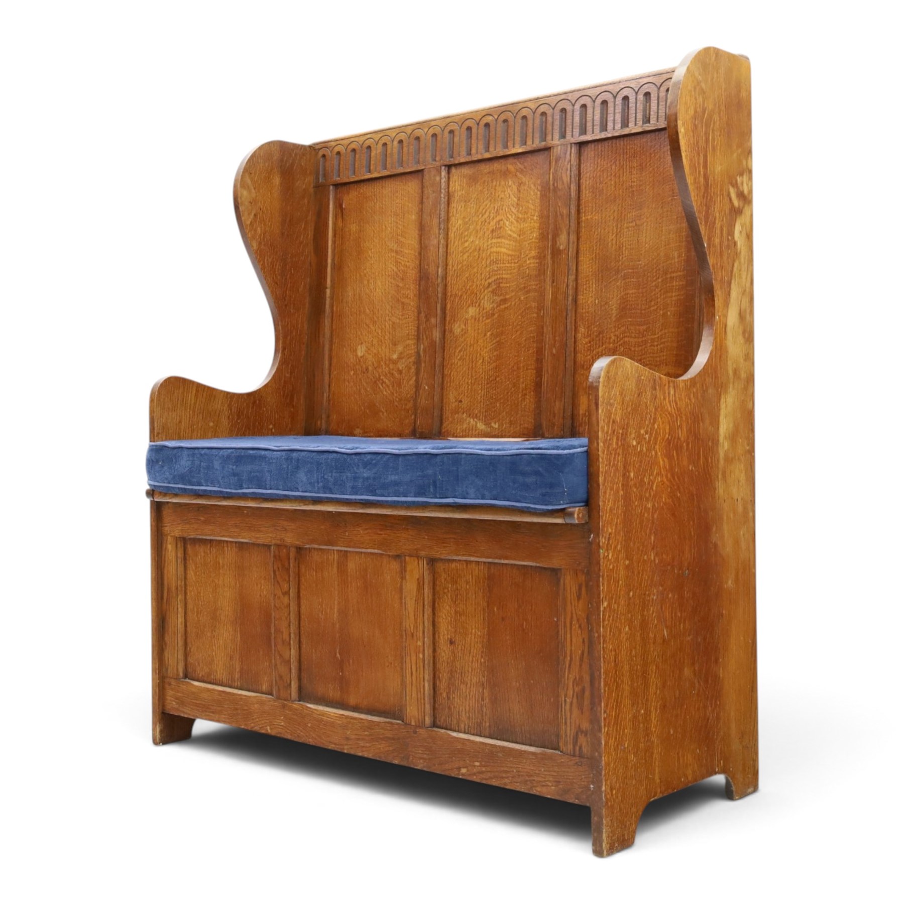 Early 20th century oak box settle, panelled back with arcaded carved rail, swept sides and arms, hinged seat with storage, panelled front
