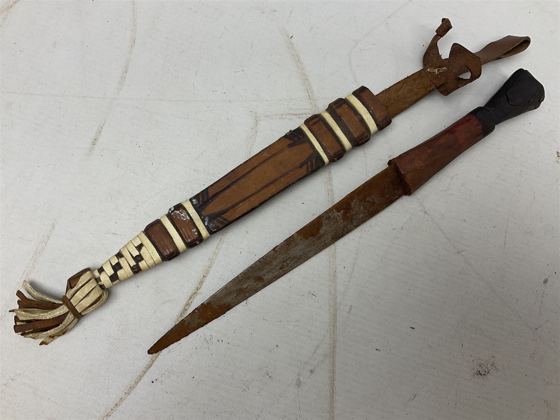 Indian kukri with 29cm curving steel blade and nickel mounted horn grip; in leather covered scabbard with one skinning knife L42cm overall; Hitler Youth knife with scabbard in relic condition; and three African graduated knives each with crudely carved wooden grips and painted leather covered scabbards (5)