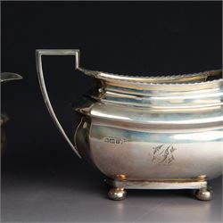 Early 20th century three piece silver tea service, comprising teapot, open sucrier and milk jug, all with oblique gadrooned rim, engraved initial to body and upon four bun feet, the teapot with Bakelite type handle and finial, hallmarked Walker & Hall, Sheffield 1912, contained within an oak presentation case with silk lining