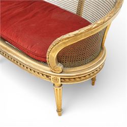 19th century giltwood and gesso settee, with shaped crest rail centred by carved floral detail, the cane back with vertical divisions, upholstered seat with loose cushion, raised on fluted tapering legs