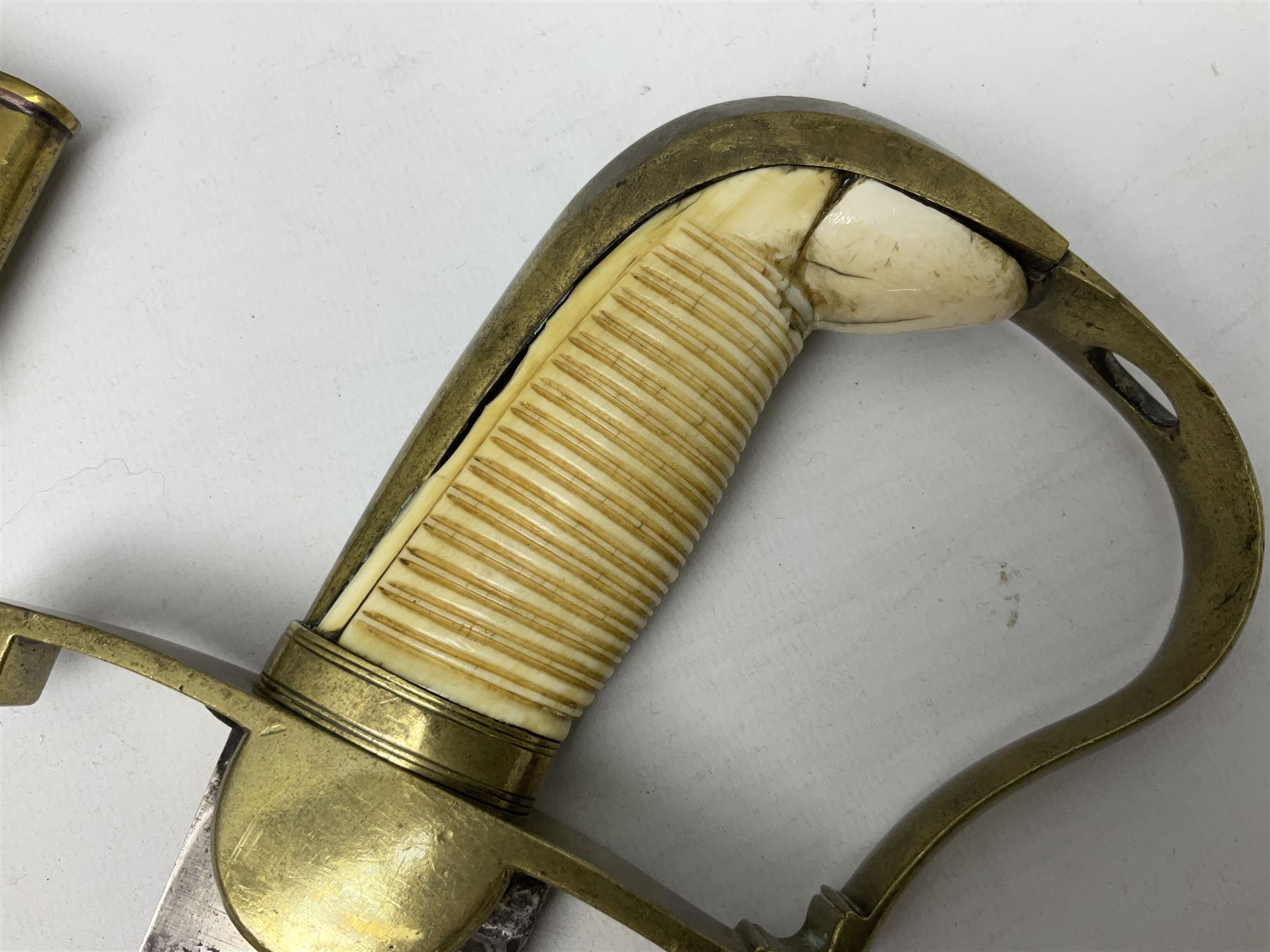 British pattern 1796 Light Cavalry Officer's sword, the 83.5cm curving steel blade marked 'W. Parker London' and 'Warranted' verso, brass stirrup hilt with half-round langets, knucklebow and backstrap with ribbed ivory grip; in brass mounted leather covered scabbard with two suspension rings L97cm overall. This item has been registered for sale under Section 10 of the APHA Ivory Act 