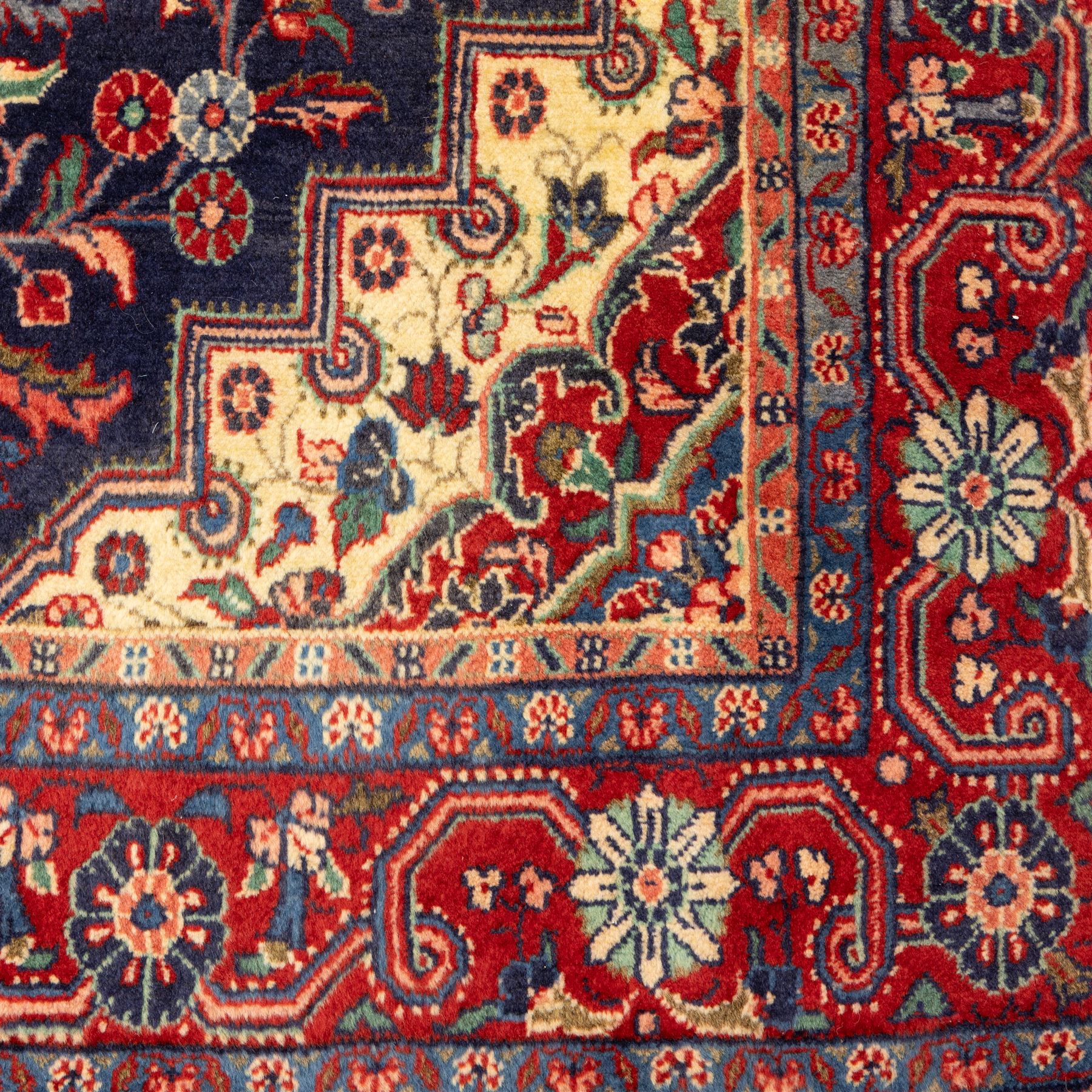 North West Persian hand-knotted Sarouk rug, central navy ground field with cusped lozenge medallion with pendant motifs, scrolling palmettes, and floral sprays, cream spandrels, and madder red border of stylized rosettes and leafy meandering vines between multiple guard stripes 