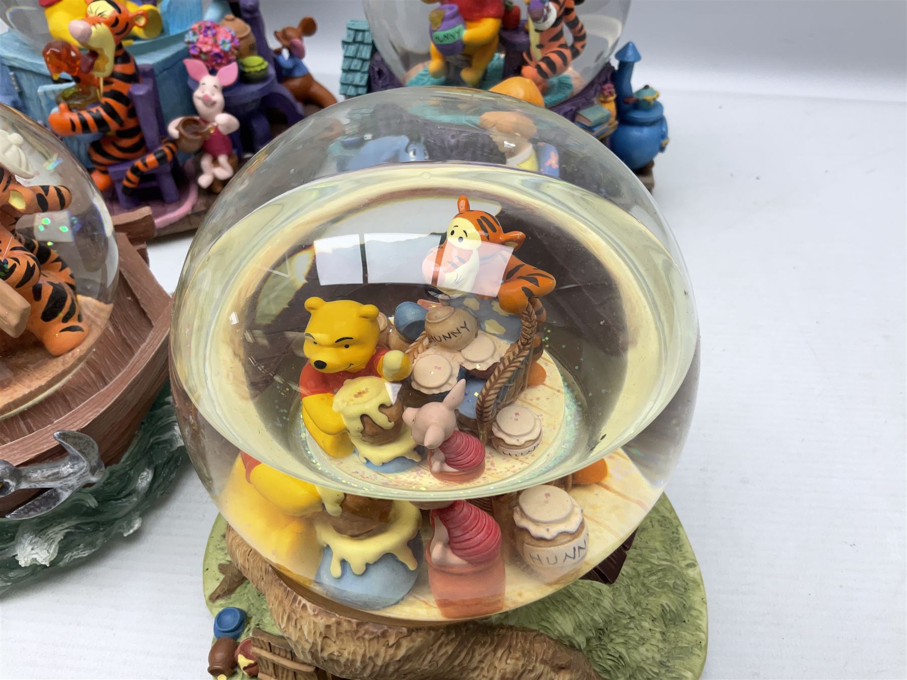 Five Disney Winnie The Pooh snow globes, to include Pooh and Piglet Sailing, Pooh's Grand Adventure and Blustery Day, together with The Walt Disney Classic Waterglobe collection globe and group Tigger, Winnie and Piglet figure under dome, all with boxes (7)