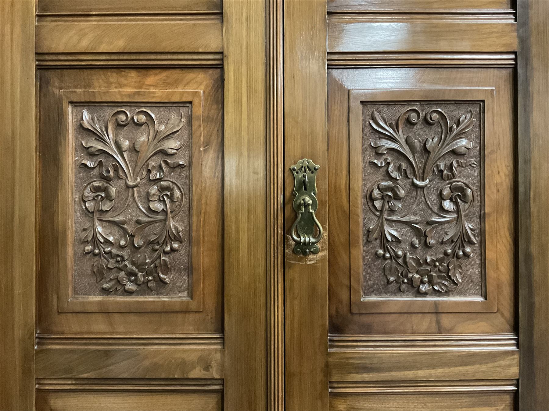 Edwardian walnut combination breakfront triple wardrobe, projecting cornice over cushioned and fluted frieze, central fielded panelled cupboard carved with foliate decoration above two short and three long drawers, flanked by two bevelled mirror doors enclosing hanging hooks with single drawers to base, retailed by J Tonks & Sons, Scarborough