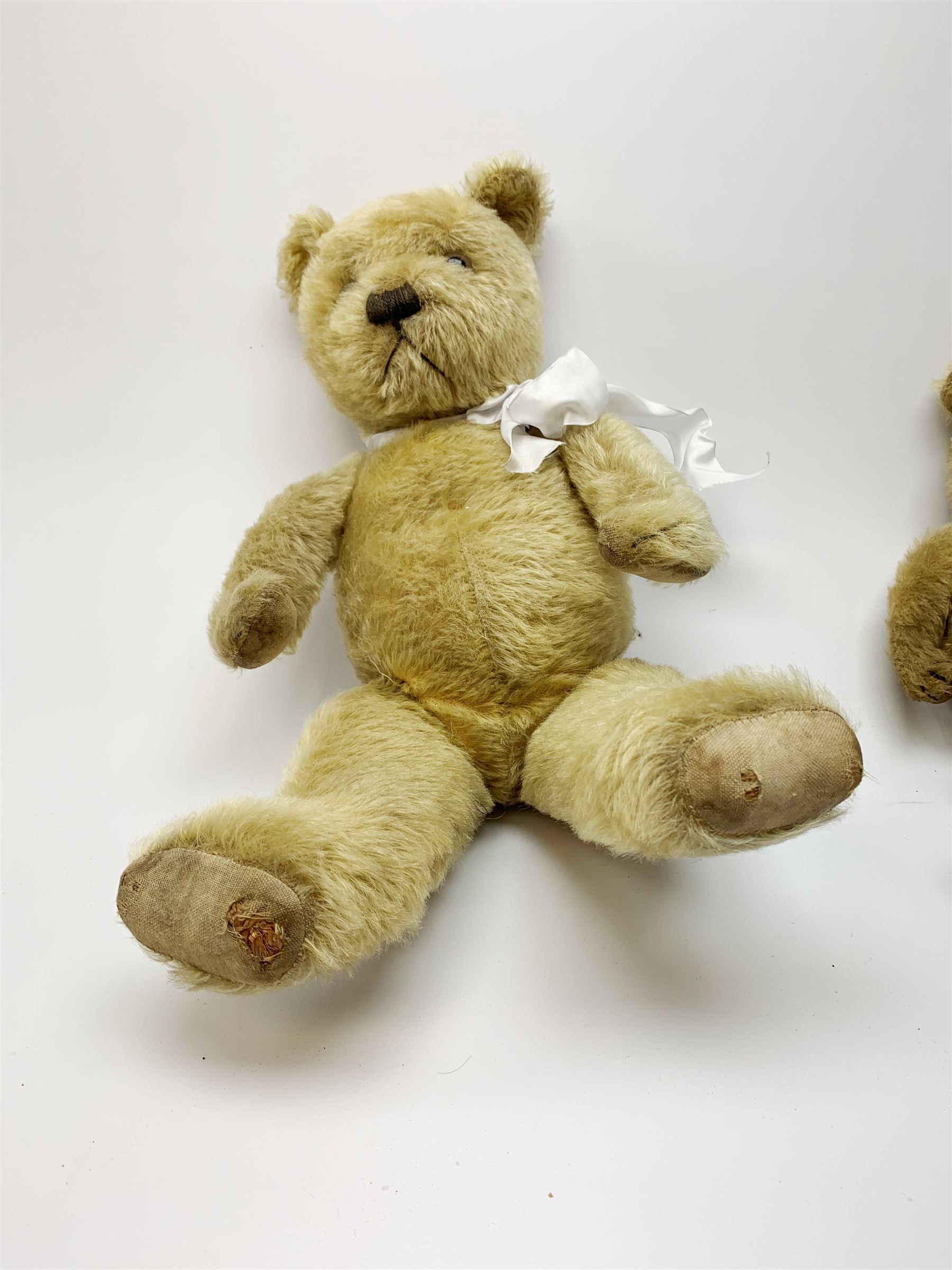 Two 1930s Chiltern type graduated teddy bears, one wood wool and one wood wool and kapok filled plush bodies, each with swivel revolving head, applied eyes and vertically stitched nose and mouth and jointed limbs, tallest H20.5