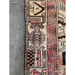 Persian Heriz red and pale ground rug, depicting multiple shaped panels with stylised motifs and designs, geometric patterned border