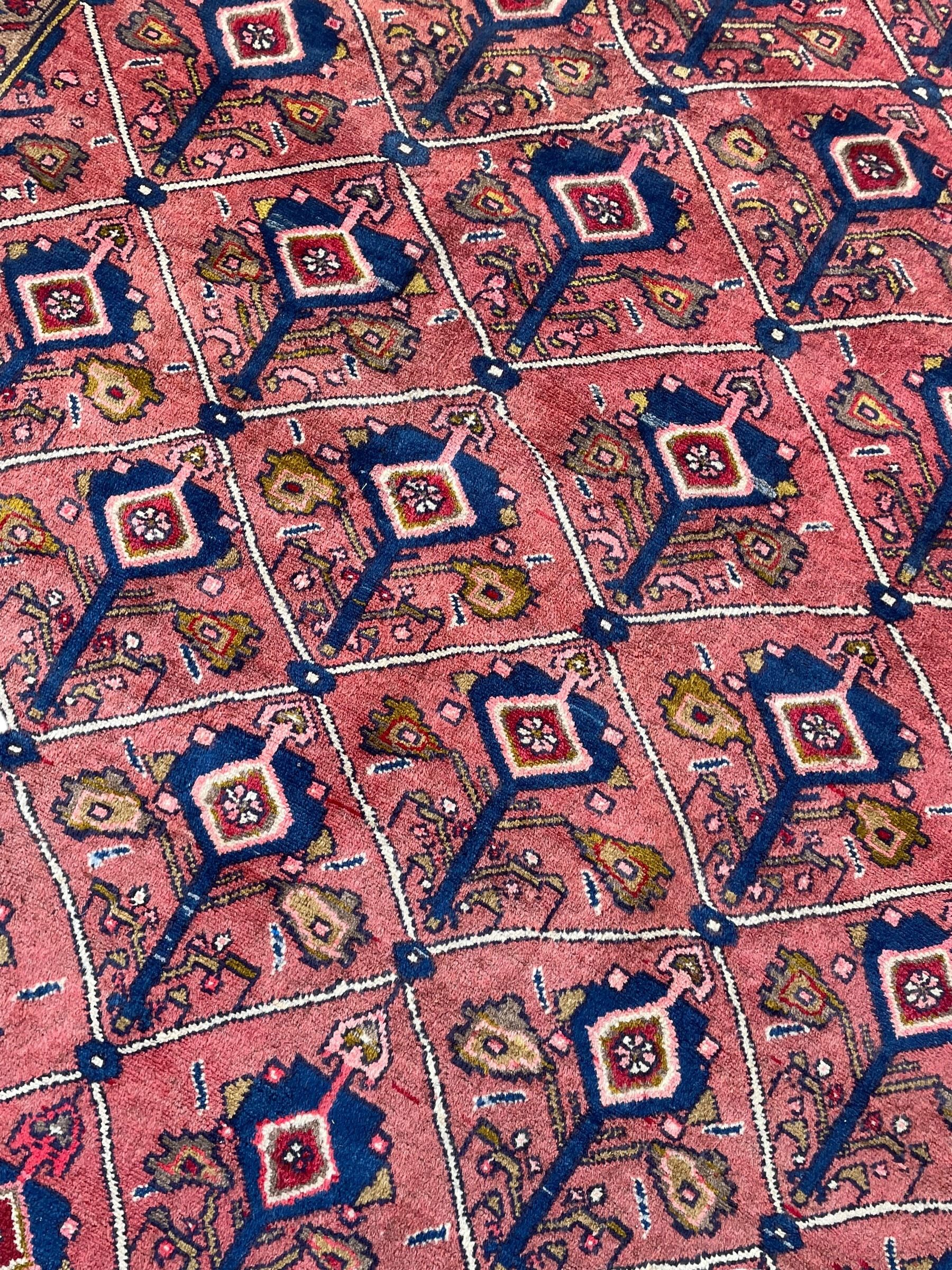 Persian Ardakan crimson ground rug, the field divided by lattice and decorated with stylised tree of life motifs, the border decorated with geometric flower heads, within guard stripes 