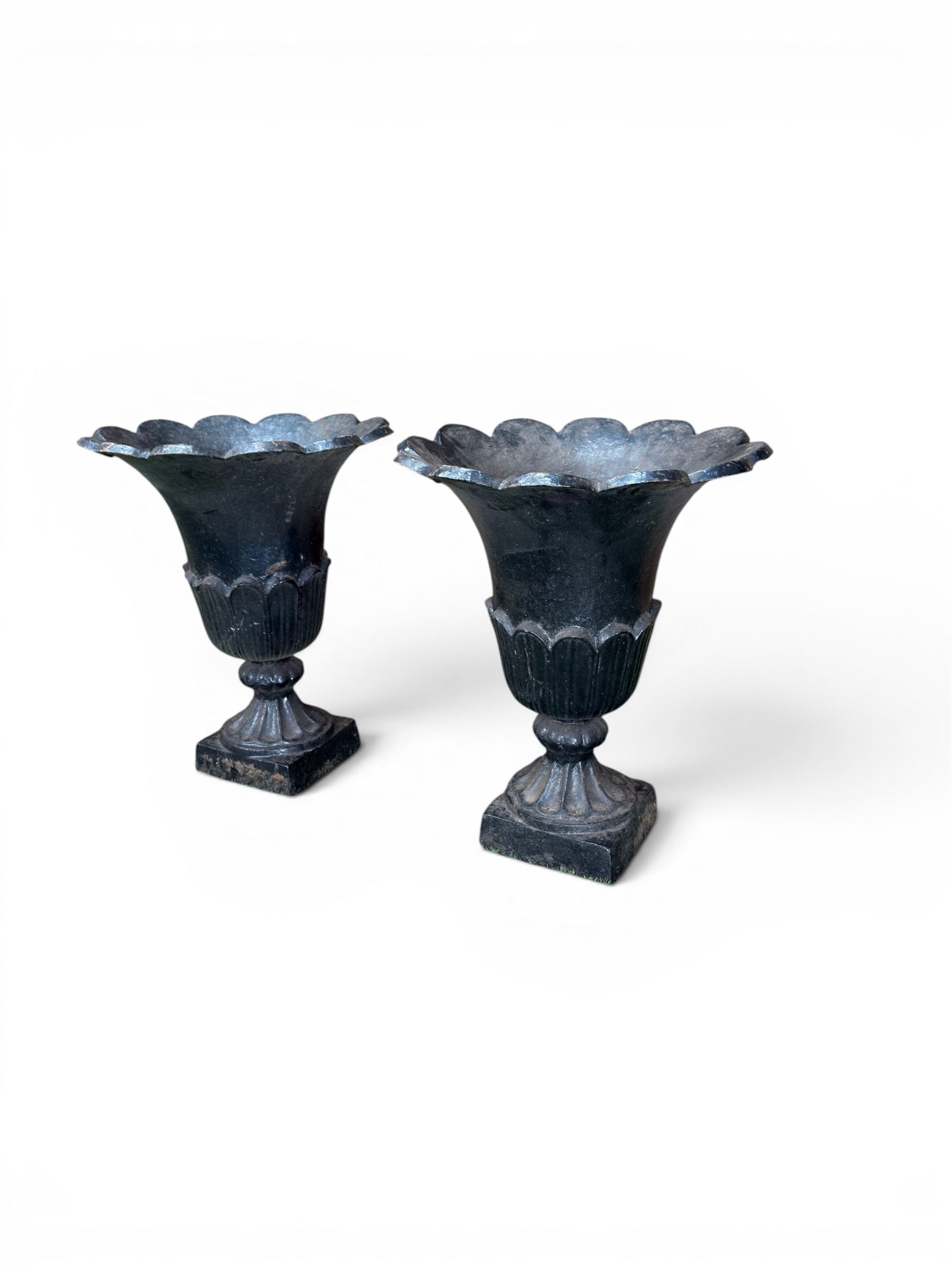 Pair of Victorian large scale cast iron garden urns, flared petal shaped rim with tapering waist, gadrooned base on square plinth, finished in black paint