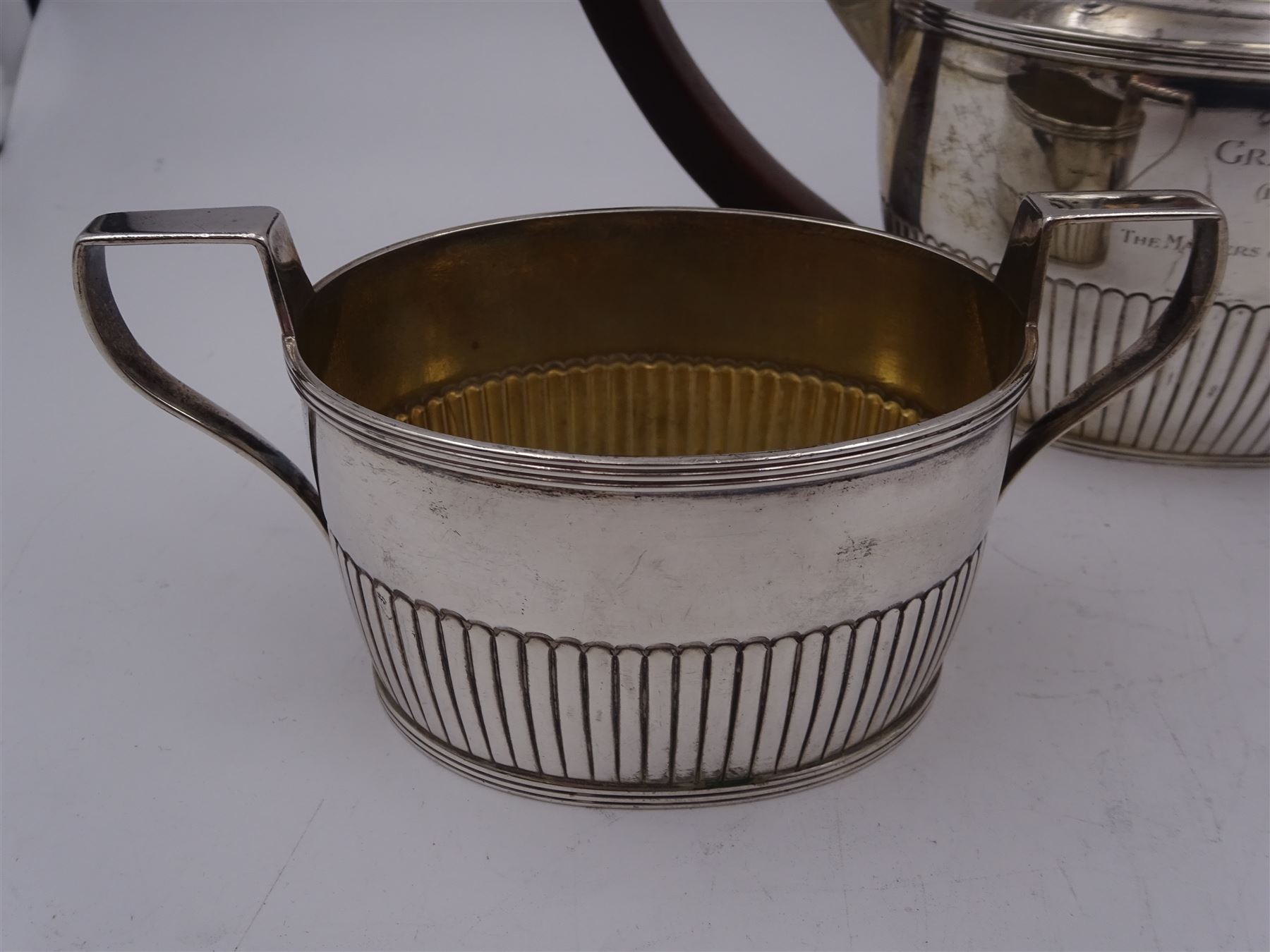 1930s American silver three piece batchelors tea service, comprising teapot, twin handled open sucrier and milk jug, each of part fluted oval form, the teapot with personal engraving to body, wood effect handle and silver urn shaped finial, stamped sterling with maker's mark for Gorham, teapot H13cm