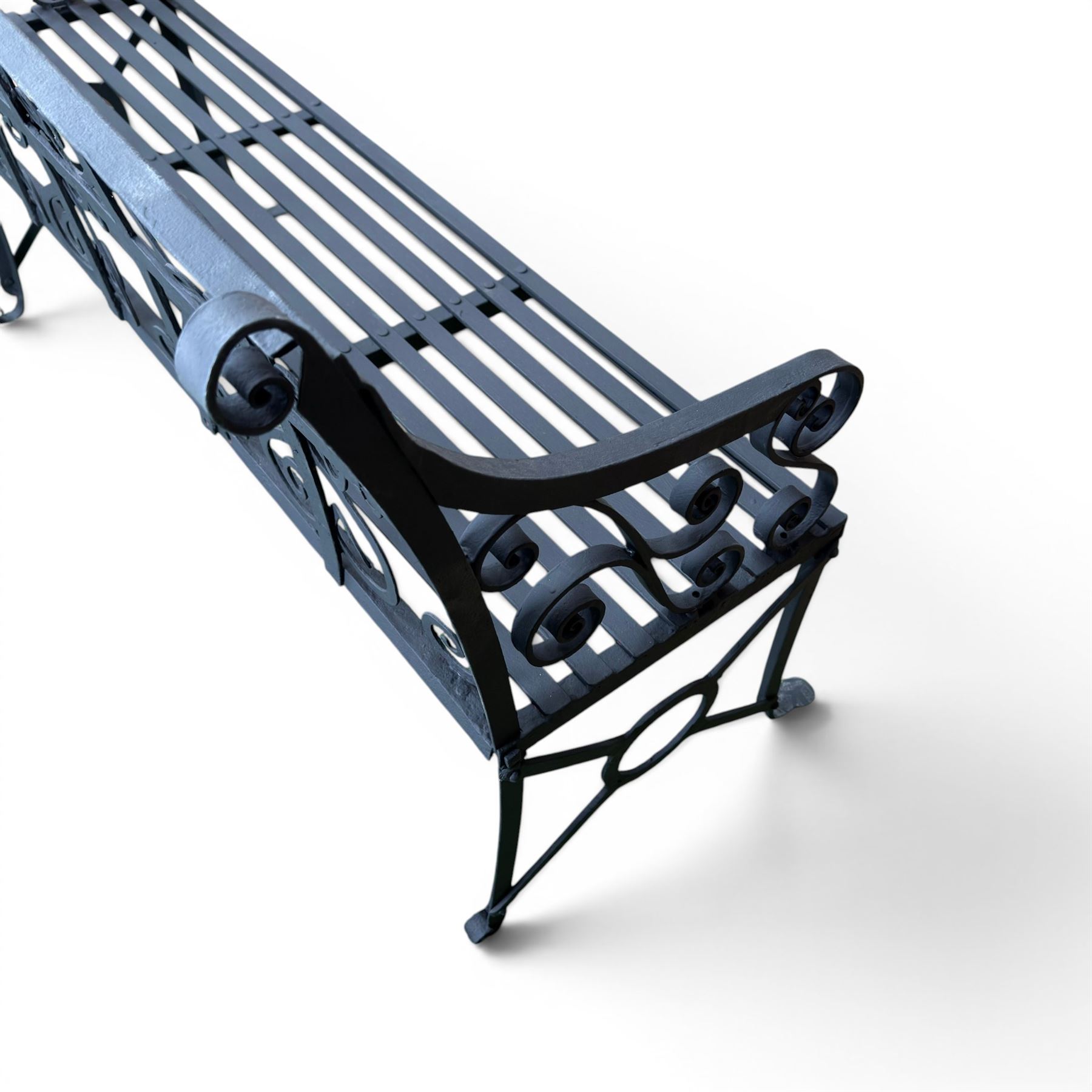 Regency period wrought iron garden bench, hand forged in wrought iron and finished in matt black paint, decorated with intricate scrollwork and featuring circular geometric ends, strapwork seat